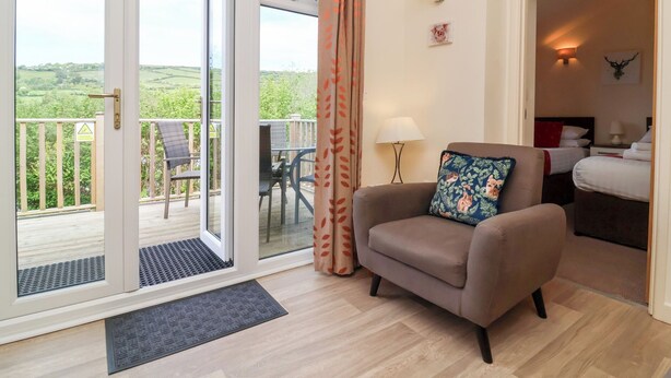 A room with a sofa, a lamp, a bed, and a view of the outdoors. - 11 Manleigh Park (Ilfracombe)