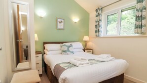 Une chambre à coucher avec un lit, des tables de chevet, un miroir et une fenêtre avec des rideaux.