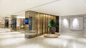 A modern lobby with a polished marble floor, a reception desk, a large potted plant, and a framed artwork on the wall. - Ji Hotel Shanghai New Jiangwan City Yingao Road (Shanghai)