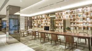 A modern conference room with a long table, multiple chairs, and a bookshelf with books. - Ji Hotel Shanghai New Jiangwan City Yingao Road (Shanghai)