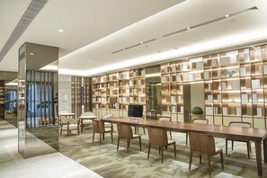 A modern conference room with a long table, multiple chairs, and a bookshelf with books. - Ji Hotel Shanghai New Jiangwan City Yingao Road (Shanghai)