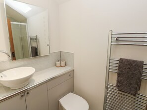 A bathroom with a white sink, a mirror, a towel rack, and a toilet.