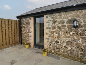 A stone building with a wooden fence, a glass door, and two potted plants.