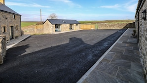 A stone building with a paved driveway and a stone wall.