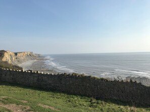 A coastal landscape with a stone wall and cliffs.
