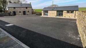 A stone building with a gravel driveway and a stone wall.