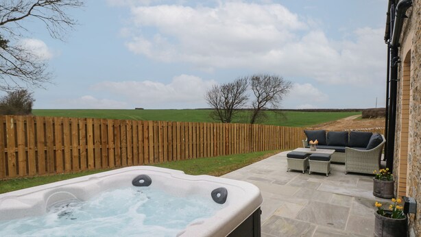 Een hottub met een houten omheining en een terras.