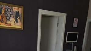 A living room with a sofa, a table, a television, and a door. - oldmile palace hotel (Istanbul)