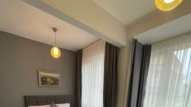 A modern hotel room with a bed, a sofa, a small table, and a picture on the wall. - oldmile palace hotel (Istanbul)