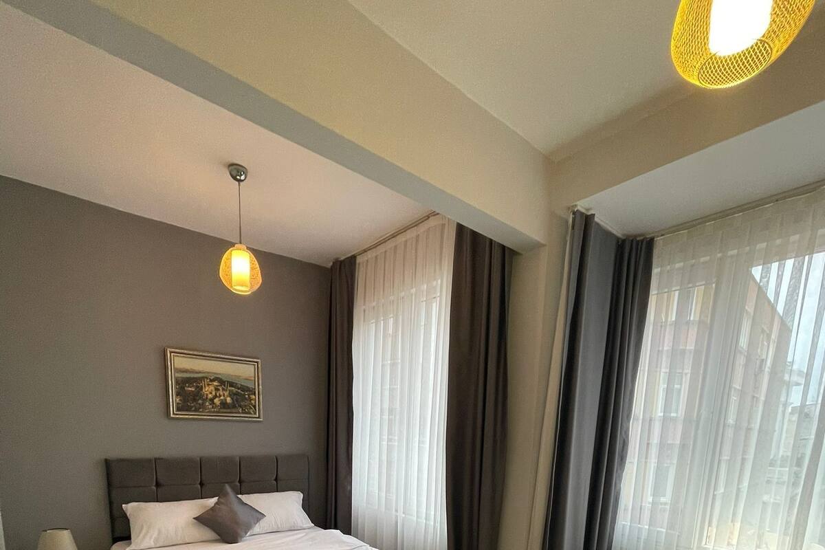 A modern hotel room with a bed, a sofa, a small table, and a picture on the wall.