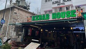 A restaurant named "Kebab House" with outdoor seating, a sign for "Oldmille Palace Hotel" in the background, and a street lamp nearby. - oldmile palace hotel (Istanbul)