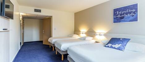 A hotel room with three single beds, a TV, and a motivational quote on the wall.