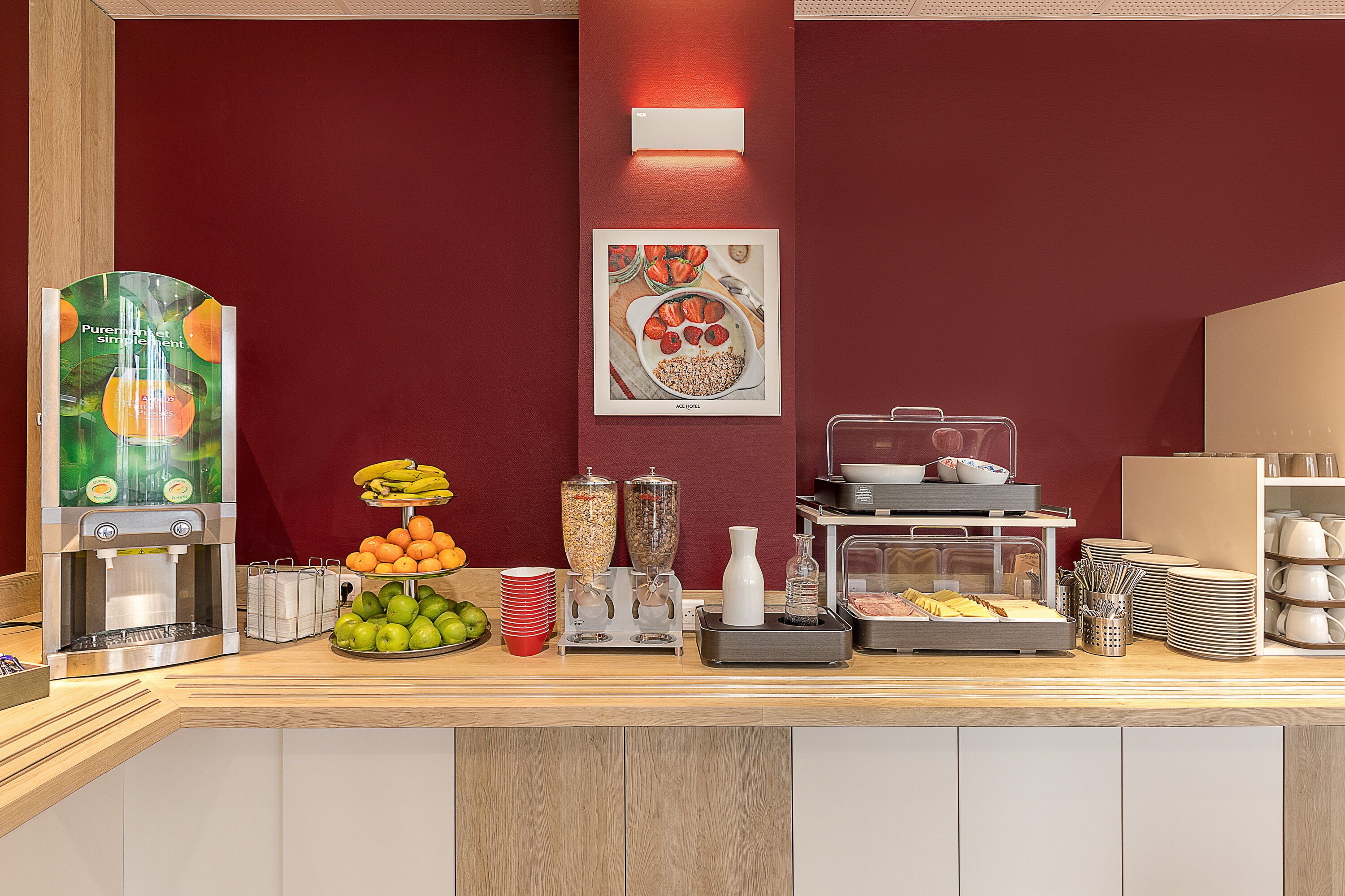Een ontbijtbuffet met een presentatie van fruit, een sapautomaat en een koffiemachine.