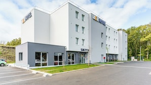 Un moderno edificio de hotel con techo plano, varias ventanas y un estacionamiento.