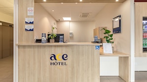 Mostrador de recepción de hotel con detalles de madera, una pantalla digital y un cartel que indica prohibido fumar.
