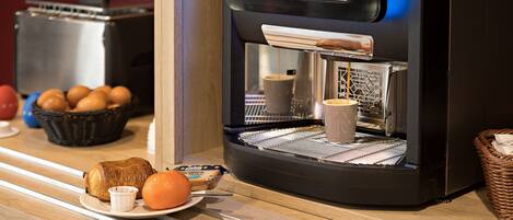 A coffee machine with a basket of eggs and a croissant on a wooden counter.