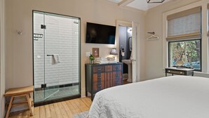 A bedroom with a large bed, a walk-in closet, a television, and a window with blinds. - La Bella Rosa, Queen Street is your backyard! (Niagara-on-the-Lake)