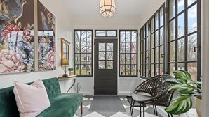 A room with a green velvet sofa, a black door, and large windows. - La Bella Rosa, Queen Street is your backyard! (Niagara-on-the-Lake)