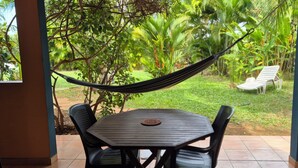 Un patio con mesa y sillas, una hamaca y vistas a un jardín exuberante.