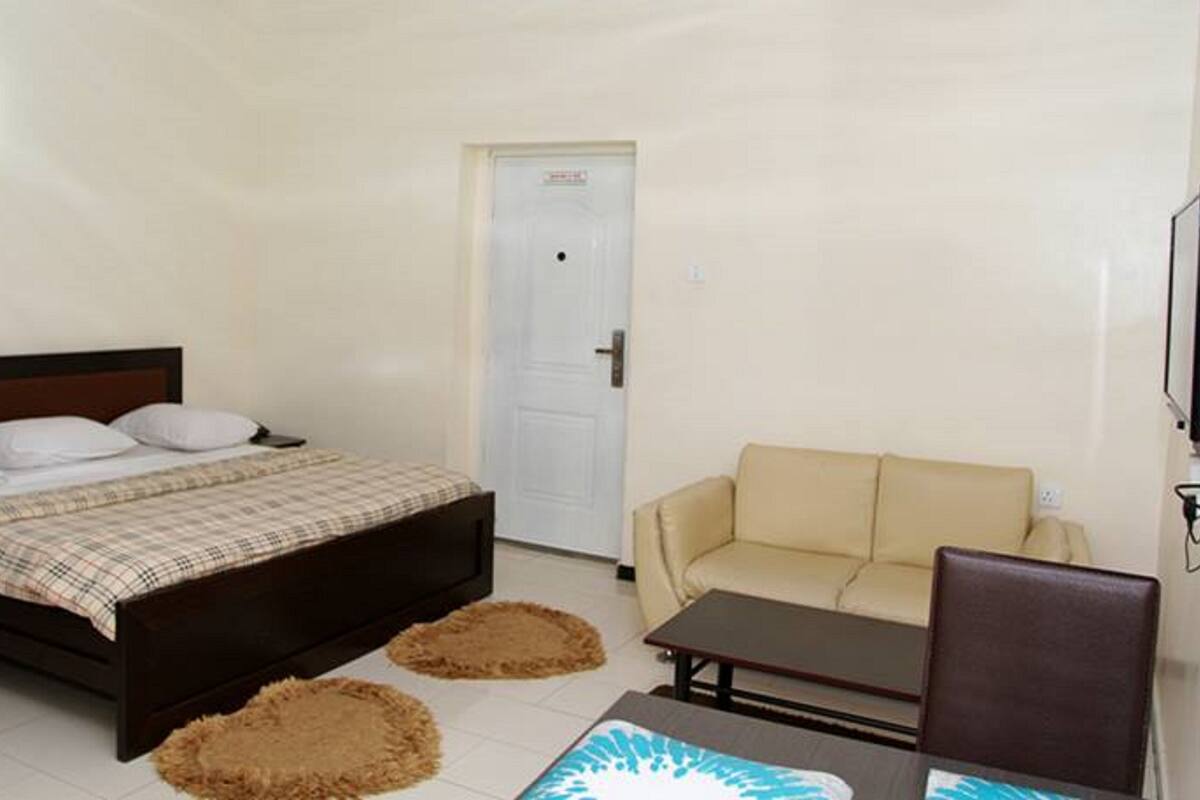 Un dormitorio con cama, sofá, televisor y puerta.