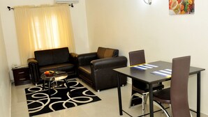 Una sala de estar con sofá, mesa de centro y mesa de comedor con sillas.