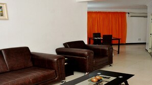 Una sala de estar con dos sofás de cuero marrón, una mesa de centro con una bandeja de pasteles y un televisor montado en la pared.