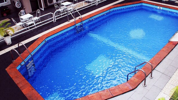 Una piscina rectangular con borde rojo y barandillas metálicas.