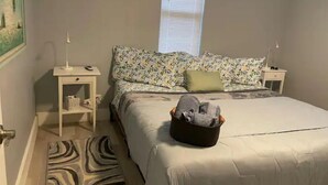 Un dormitorio con cama, mesitas de noche, una ventana y una alfombra.