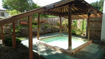 Una terraza de madera con piscina, rodeada de rocas y plantas.