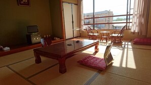 A traditional Japanese room with tatami flooring, a low wooden table, and a view of the city through large windows. - Nakanosawa Onsen Ryokan Shirokiya (Inawashiro)