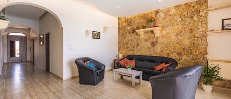 A living room with a stone wall, a sofa, two armchairs, a coffee table, and a potted plant.