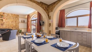 Una zona de dinar amb taula preparada per a quatre, una cuina amb vistes i un saló amb sofà.
