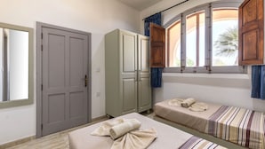 Habitació amb dos llits, un armari i una finestra amb cortines.