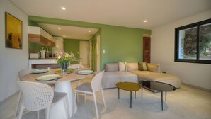 A modern living space with a dining area, a sofa set, and a kitchen in the background. - 2 CHAMBRES JARDIN/TERRASSE ACCES PLAGES A2B241 (Cannes)