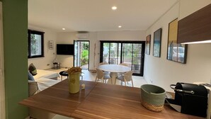 A modern kitchen with a central island, dining area with chairs, and a TV mounted on the wall. - 2 CHAMBRES JARDIN/TERRASSE ACCES PLAGES A2B241 (Cannes)