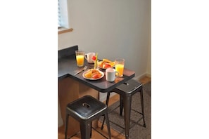 Enjoy a convenient kitchenette with a plate of fresh fruits and a glass of juice, perfect for a quick breakfast.