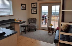Cozy living space with a kitchenette, dining area, and seating area, featuring a balcony with a view of the surrounding landscape.