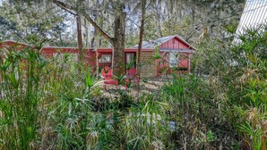 A row of red cabins surrounded by dense vegetation. - Little Palm Hideaway Cottage (St. Augustine)