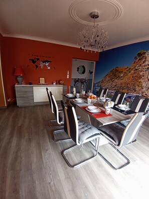 Un espace repas avec une longue table, des chaises modernes et un lustre.