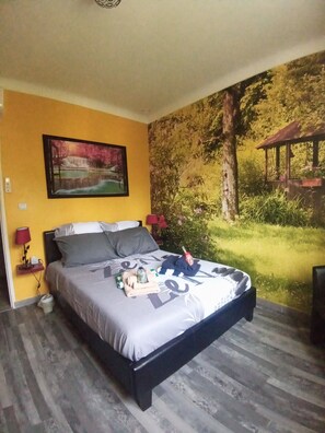 Une chambre à coucher avec un lit, une table de chevet, une lampe et une fresque murale.