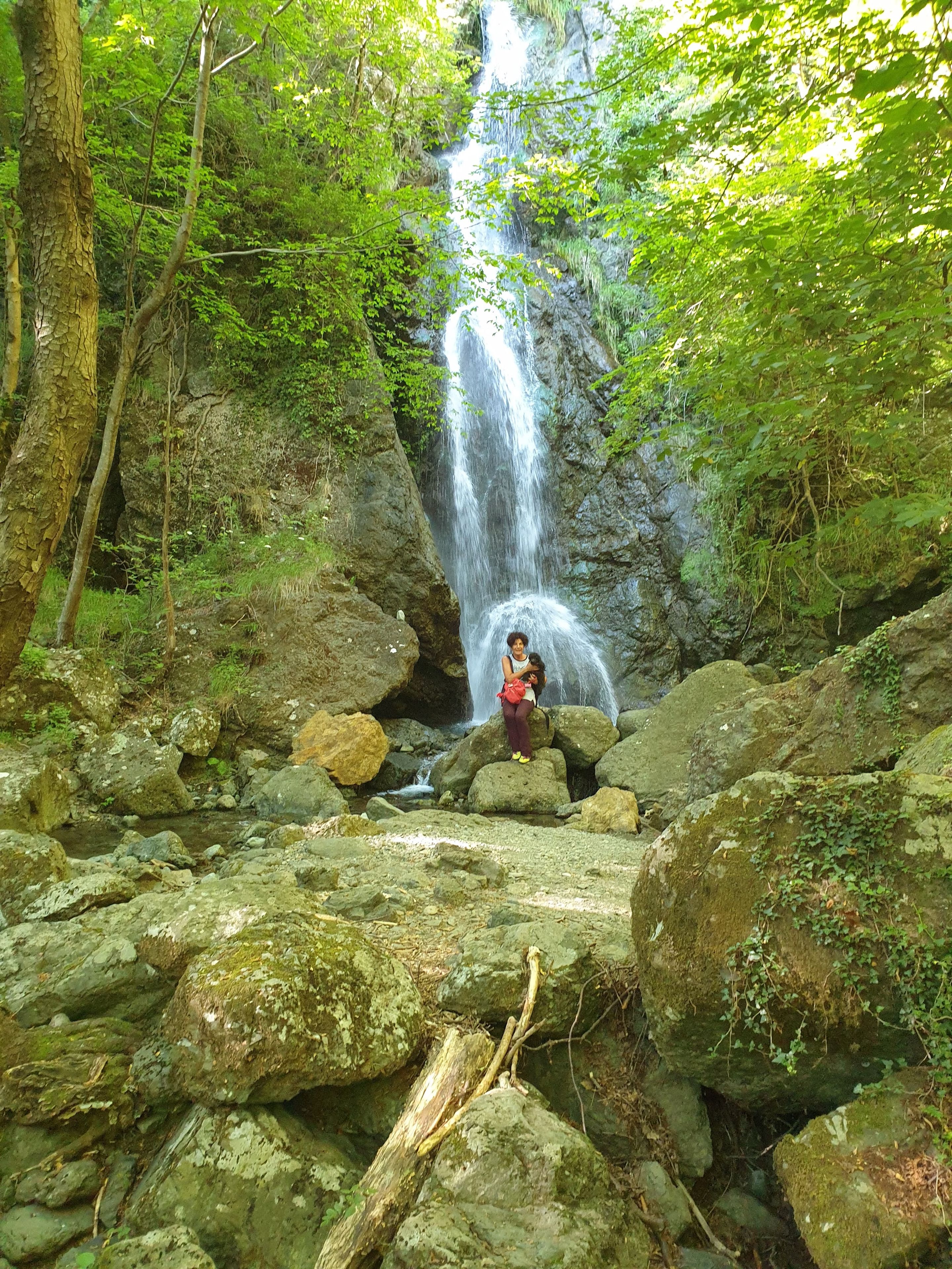 A natural waterfall surrounded by rocks and greenery.