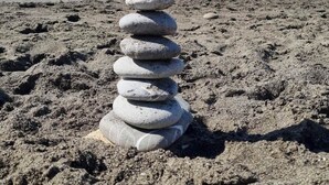 A stack of stones on a sandy beach with the ocean in the background. - La Casa Di Edy (Prato)