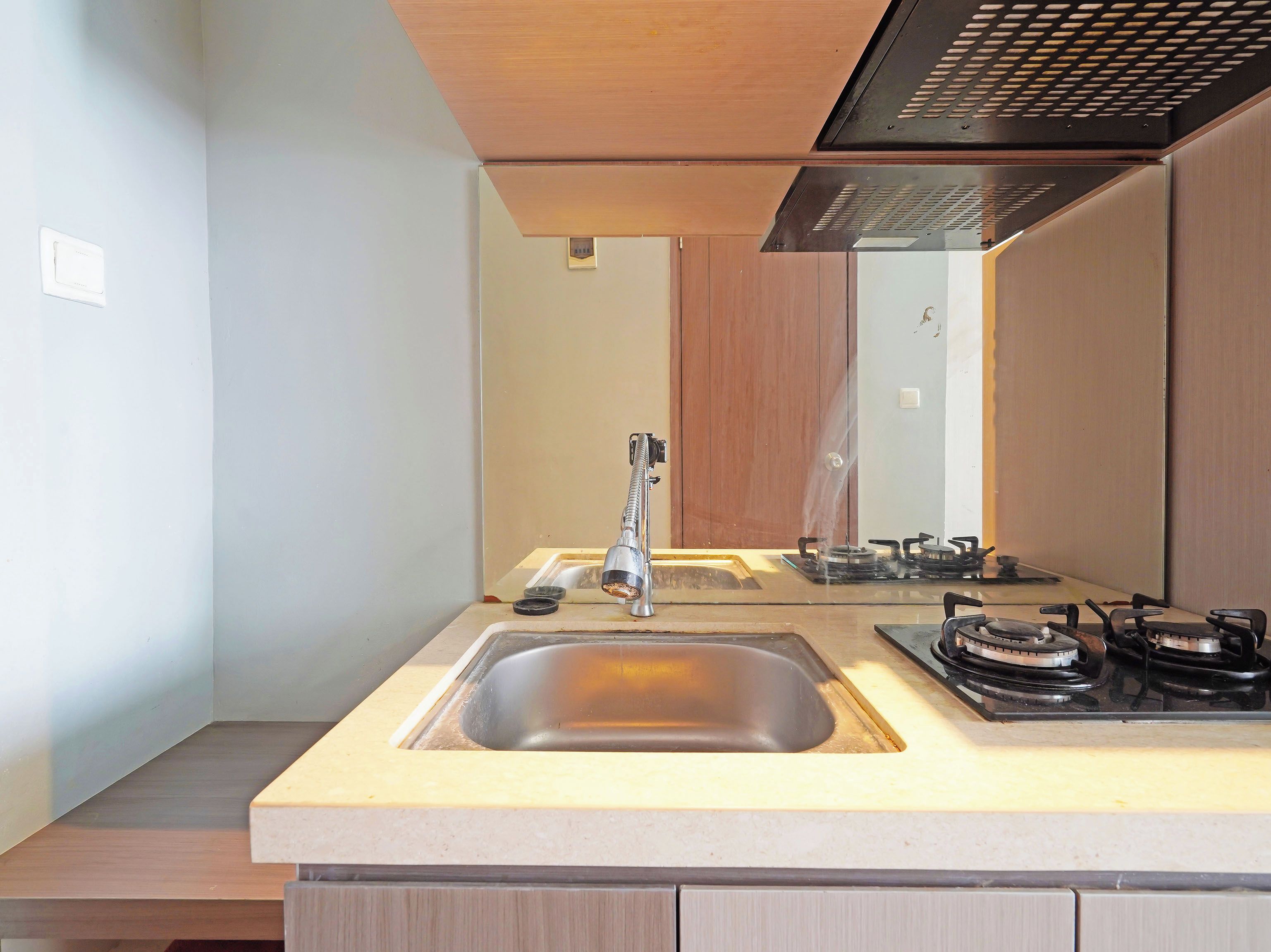 A modern kitchen with a built-in sink, a stove, and a mirror above the countertop.