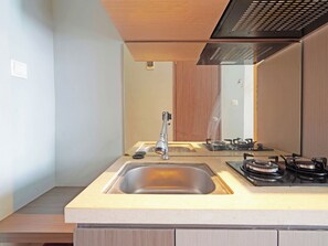 Een moderne keuken met een roestvrijstalen spoelbak, een gasfornuis en een houten kast.