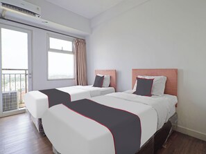 Ein Hotelzimmer mit zwei Betten, einem großen Fenster und einer Klimaanlage.