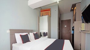 Ein Hotelzimmer mit einem Bett, einem Kleiderschrank, einem Spiegel, einem Fernseher und einer Tür.
