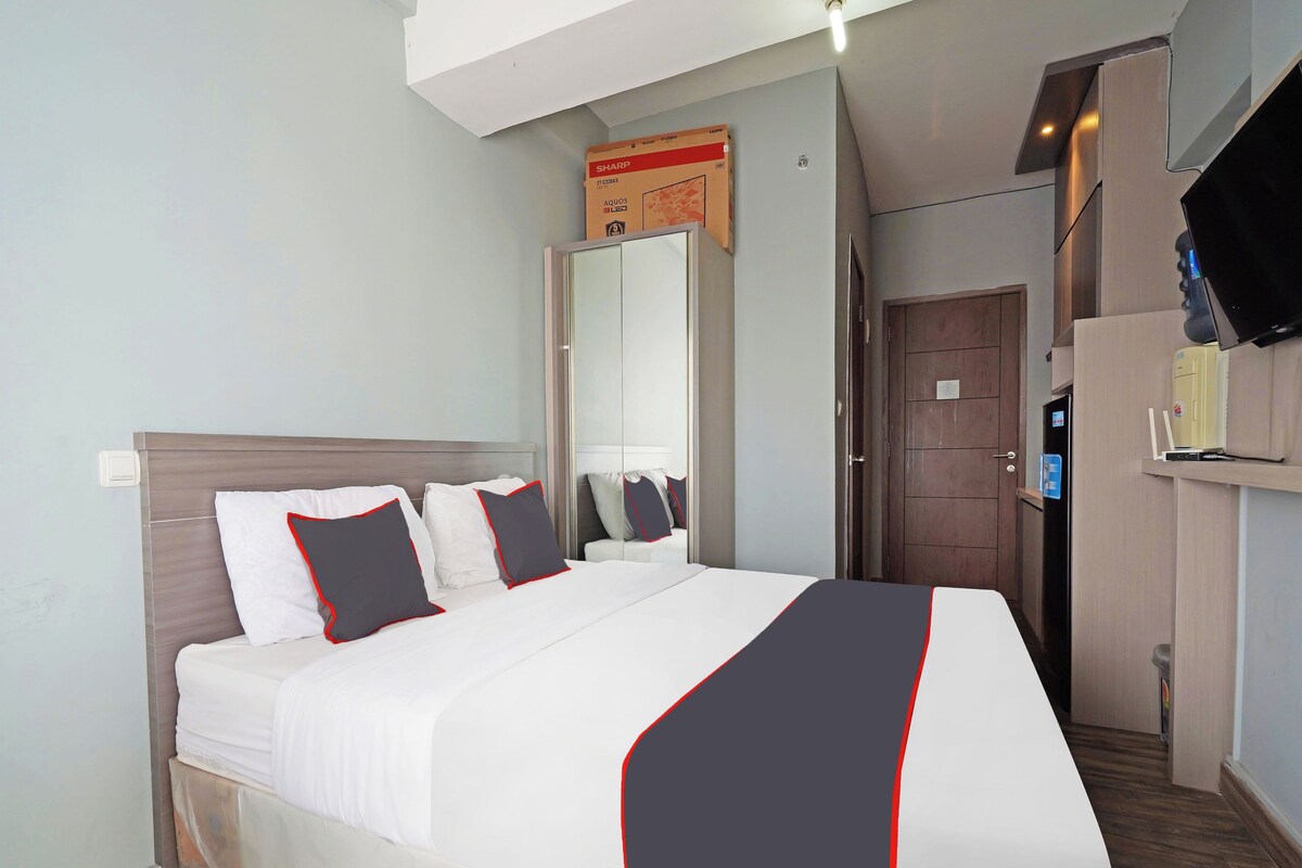 Een hotelkamer met een bed, een kledingkast, een spiegel, een televisie en een deur.