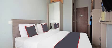 Una habitación de hotel con una cama, un armario, un espejo, un televisor y una puerta.