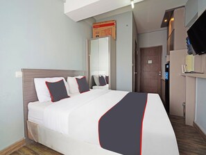 Ein Hotelzimmer mit einem Bett, einem Kleiderschrank, einem Spiegel, einem Fernseher und einer Tür.