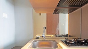 Eine moderne Küche mit Spüle aus Edelstahl, einem Gasherd und einem Holzkorpus.